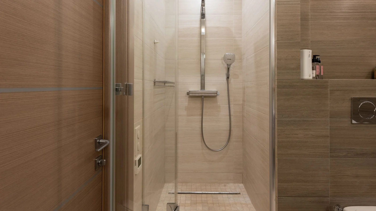 Douche vitrée au carrelage effet bois, colonne de douche chromée et siphon de sol linéaire